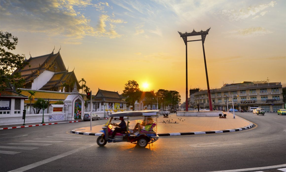 Traffic circle in Bangkok with rickshaw in front and sunset behind: bangkok bike tours