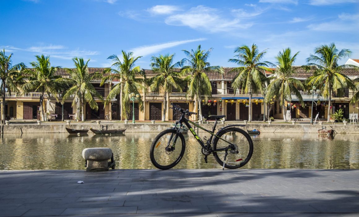 Bike parked in front of buildings and canal in Hoi An