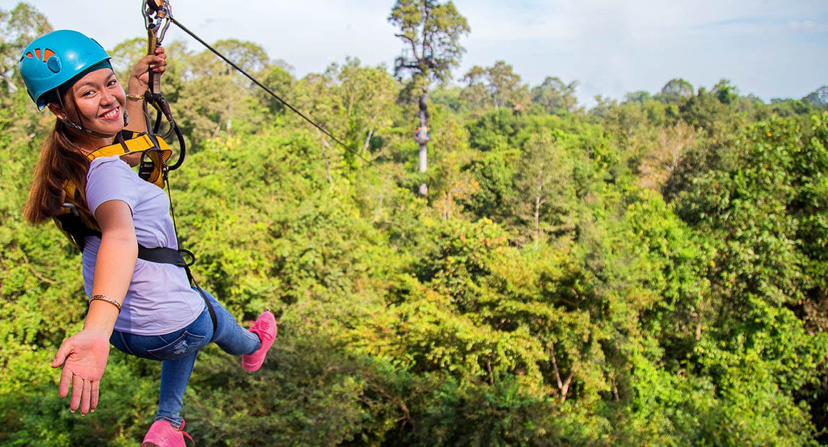 Young woman on zipline over treetops of Angkor park