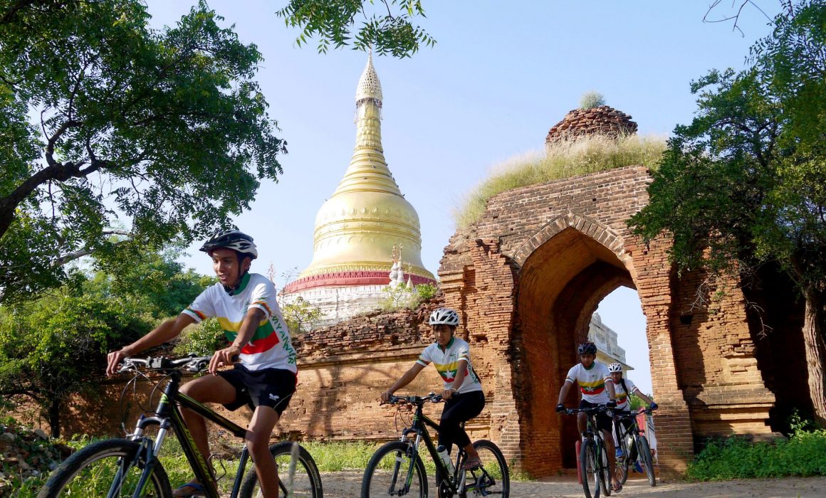 Cyclists riding under archway in Bagan