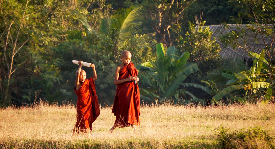 Two young monks, one with something above his head, in countryside of Myanmar