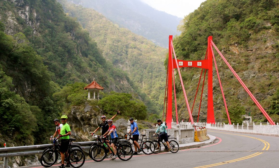 Cyclists stopped after red suspension bridge in Taroko Gorge National Park