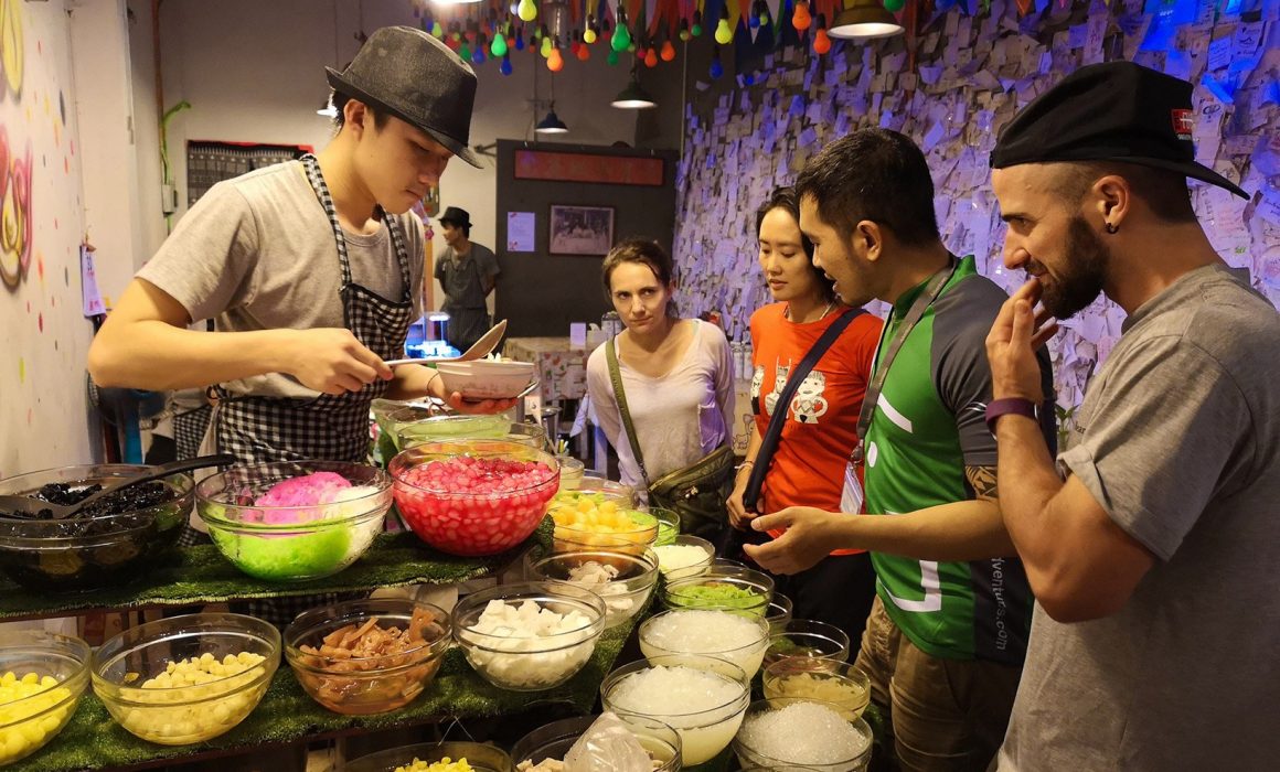 Four people being served by one man in front of a buffet of various local specialities in Chiang Mai