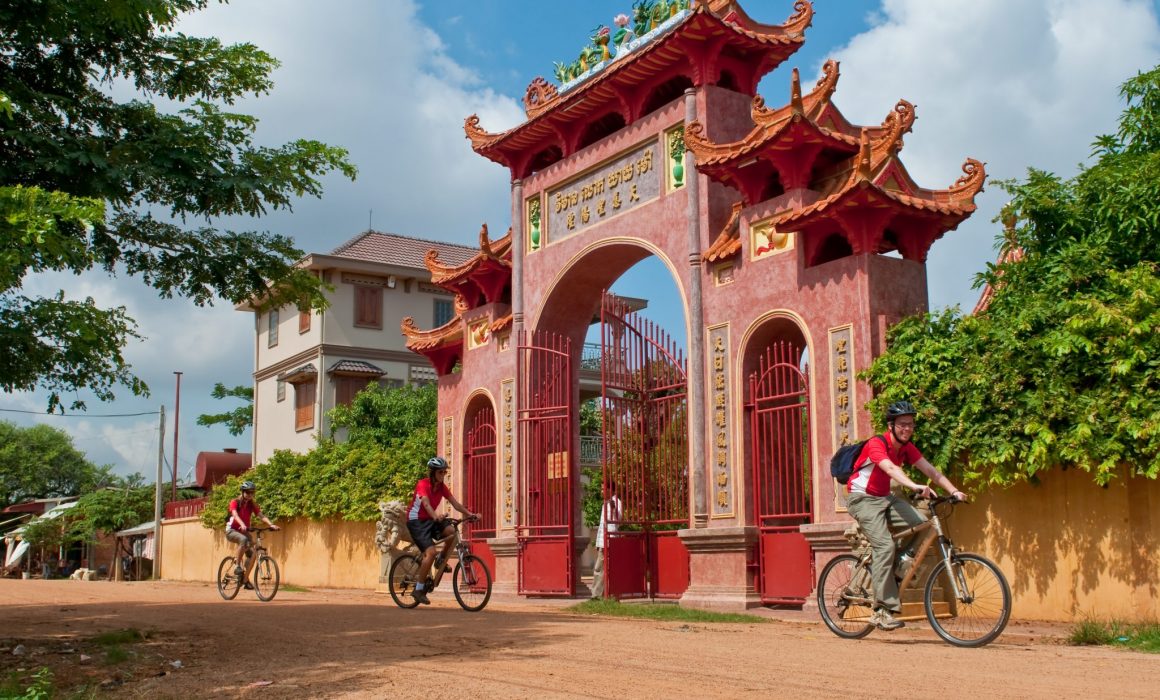 Three cyclists riding past red gate