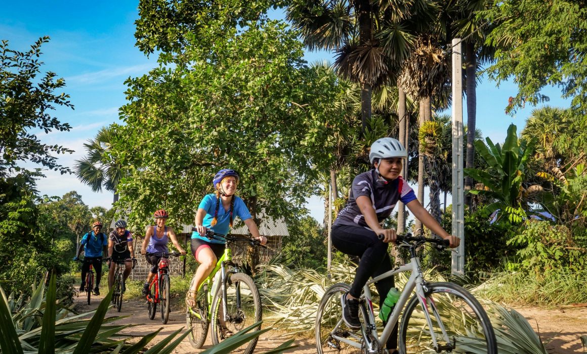 Cyclists led by guide through countryside of Cambodia