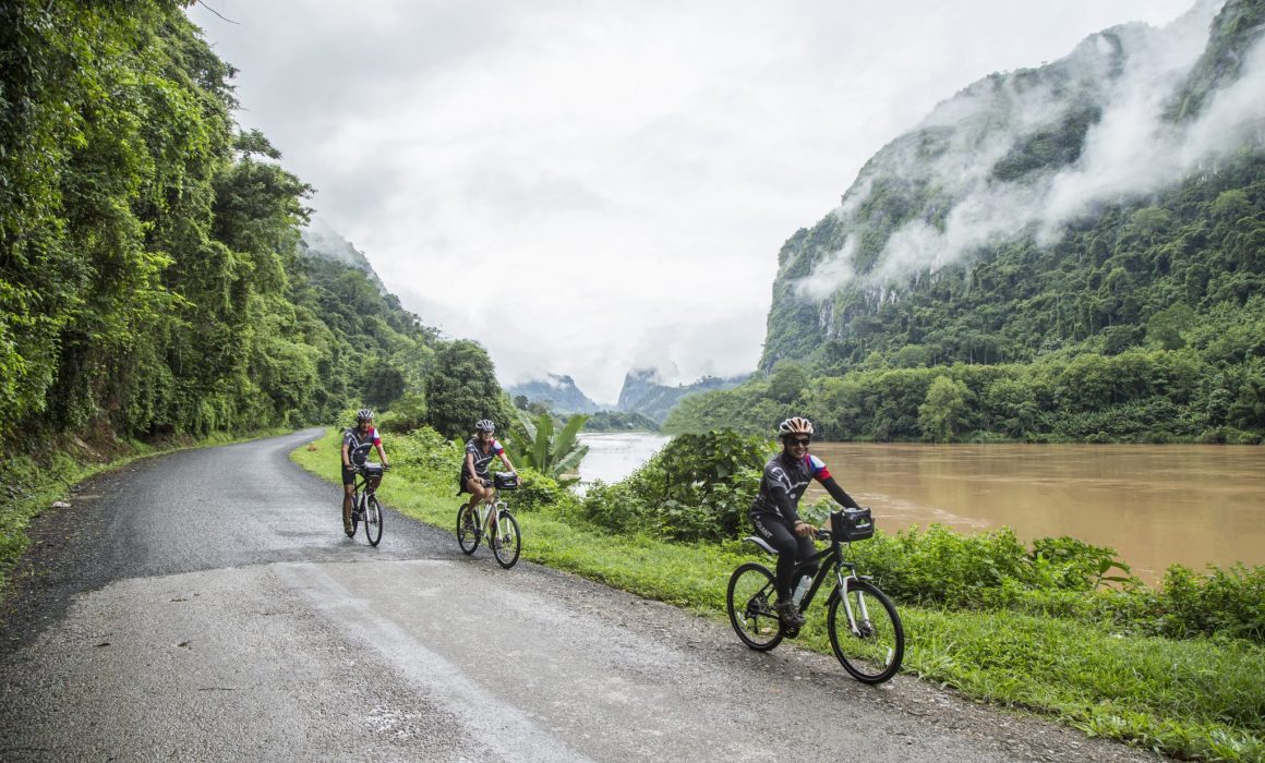 Three cyclists riding on road past river