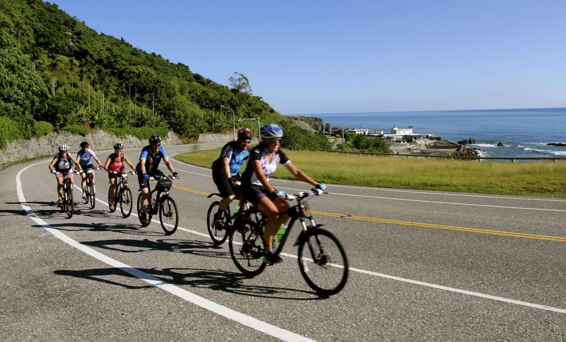 Cyclists on winding road past coastline of Taiwan