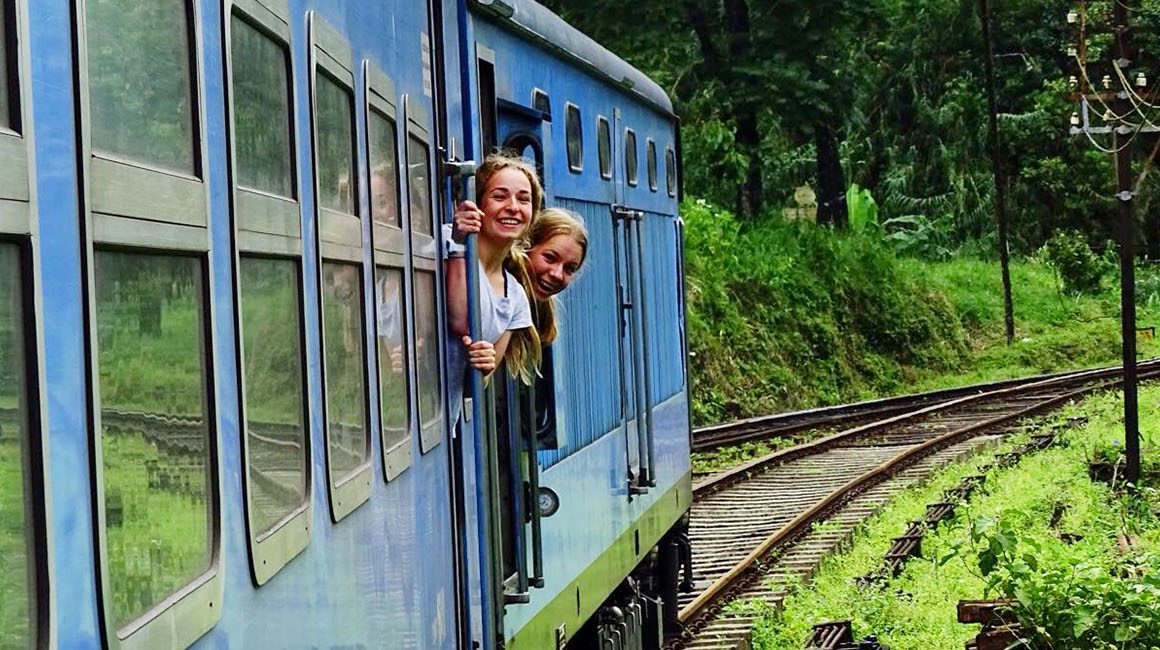 Two young women leaning out from blue train