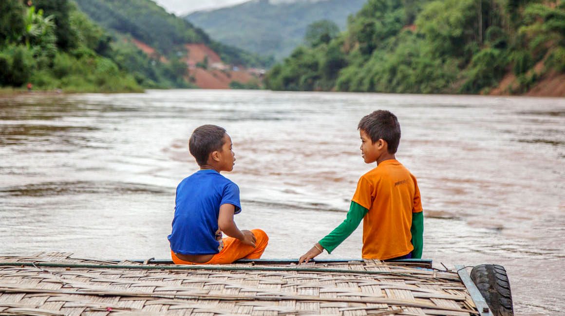 Two young local boys on boat on river in Laos