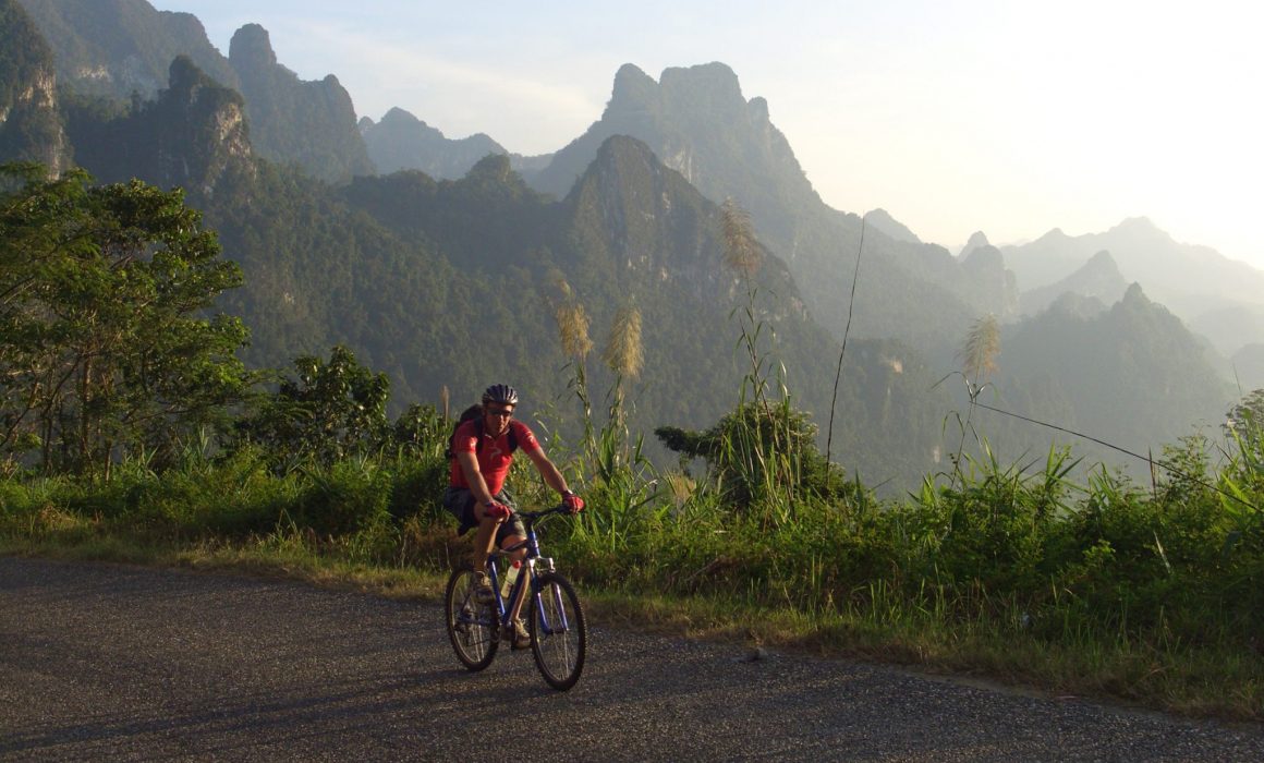 Cyclist riding on road with mountains in the background