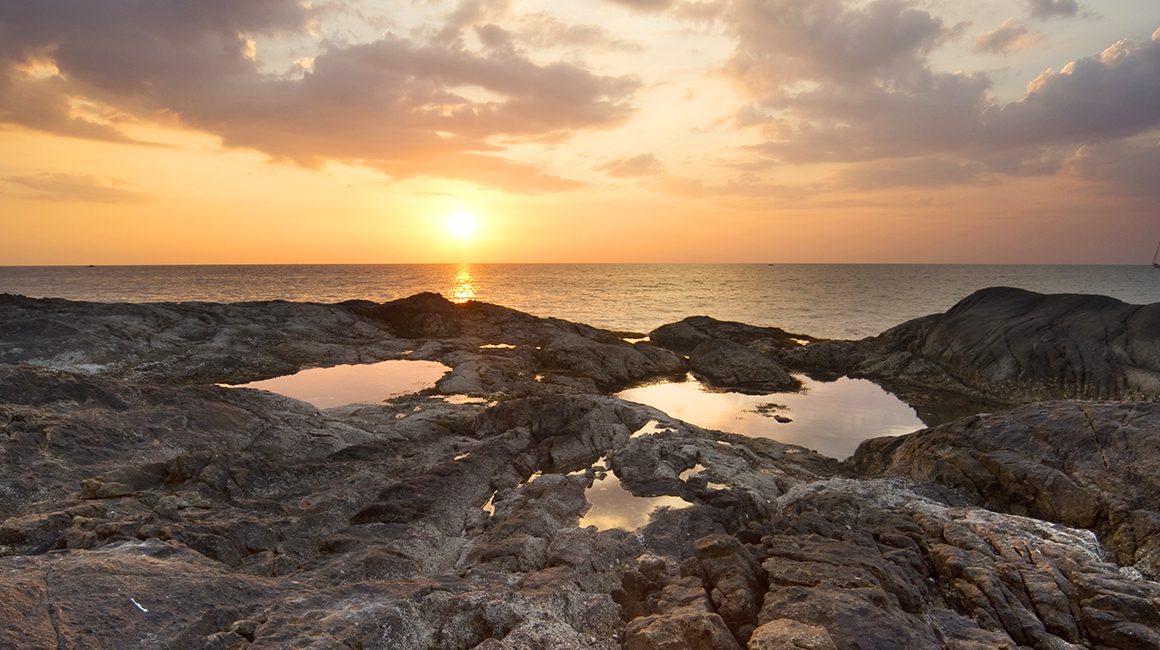 Sunset over the water with reflection in rock pools in Thailand