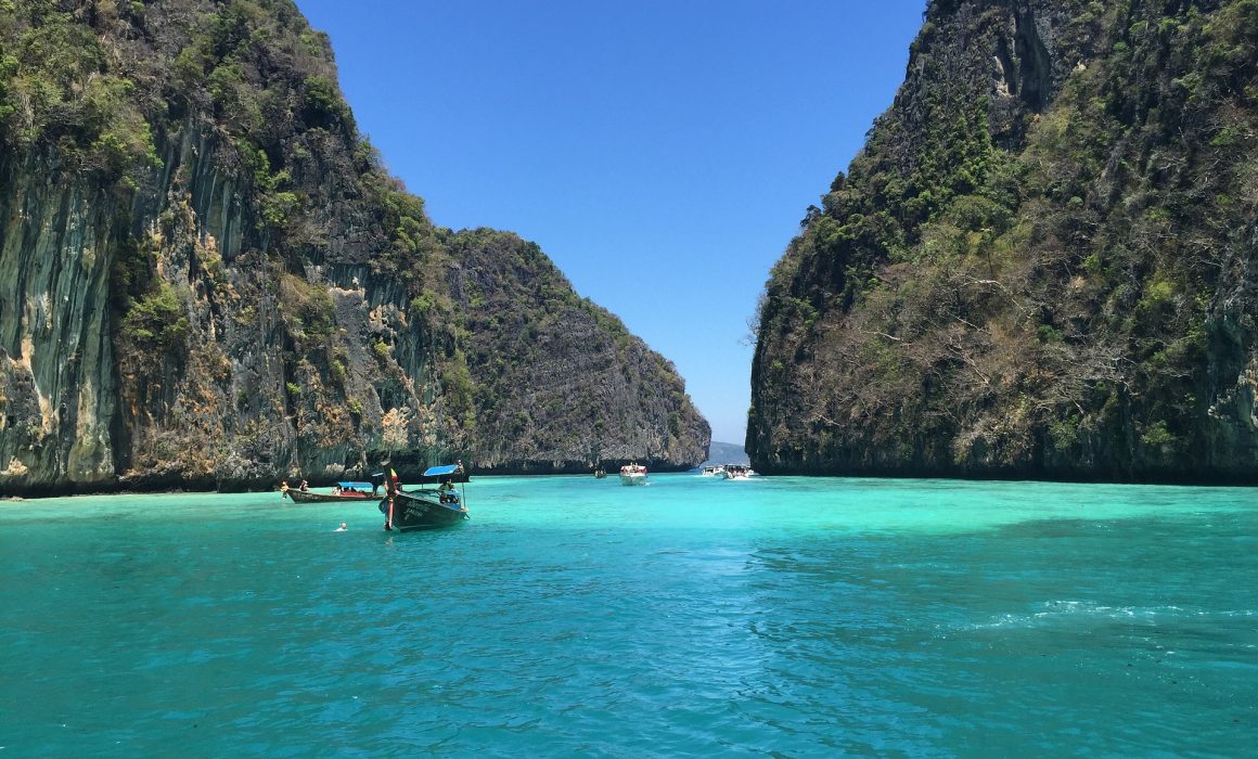 Limestone karsts and aquamarine water with boats on it