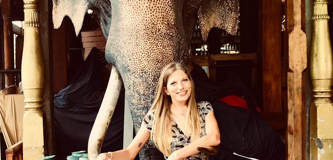 Woman in front of elephant tusks on self guided tour