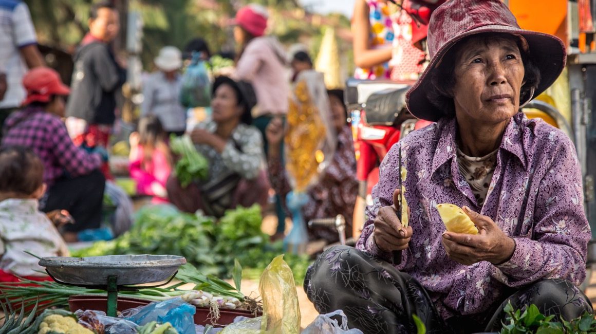 Local woman cutting fruit at vegetable market in Bangkok