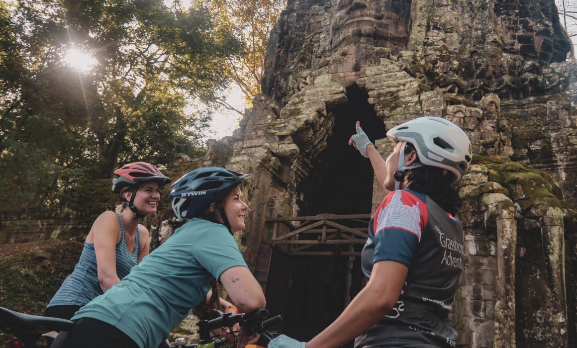 Guide pointing out something at gate to two female cyclists