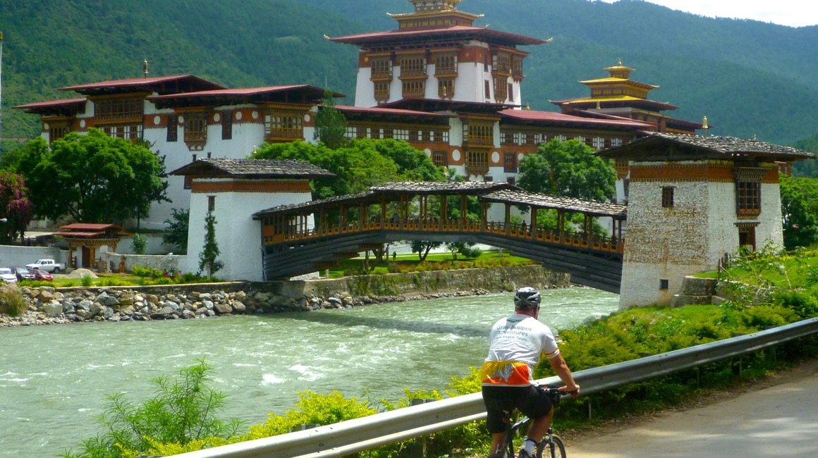 Cyclist riding past dzong and river