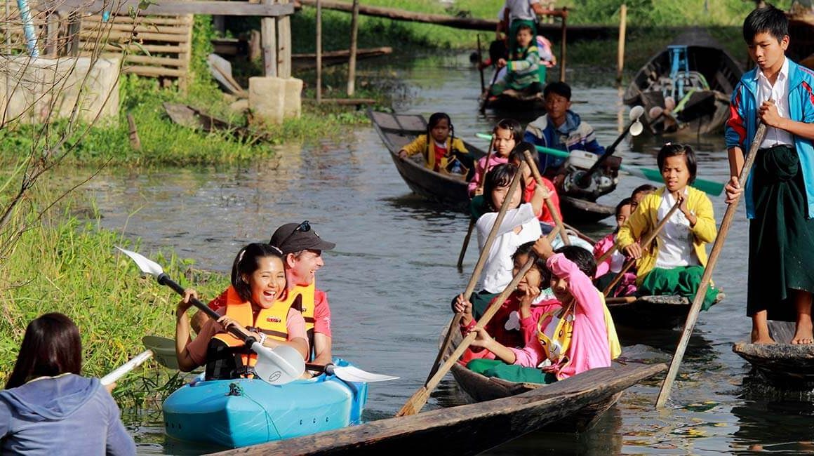 Locals rowing past tourists in kayak on Inle Lake