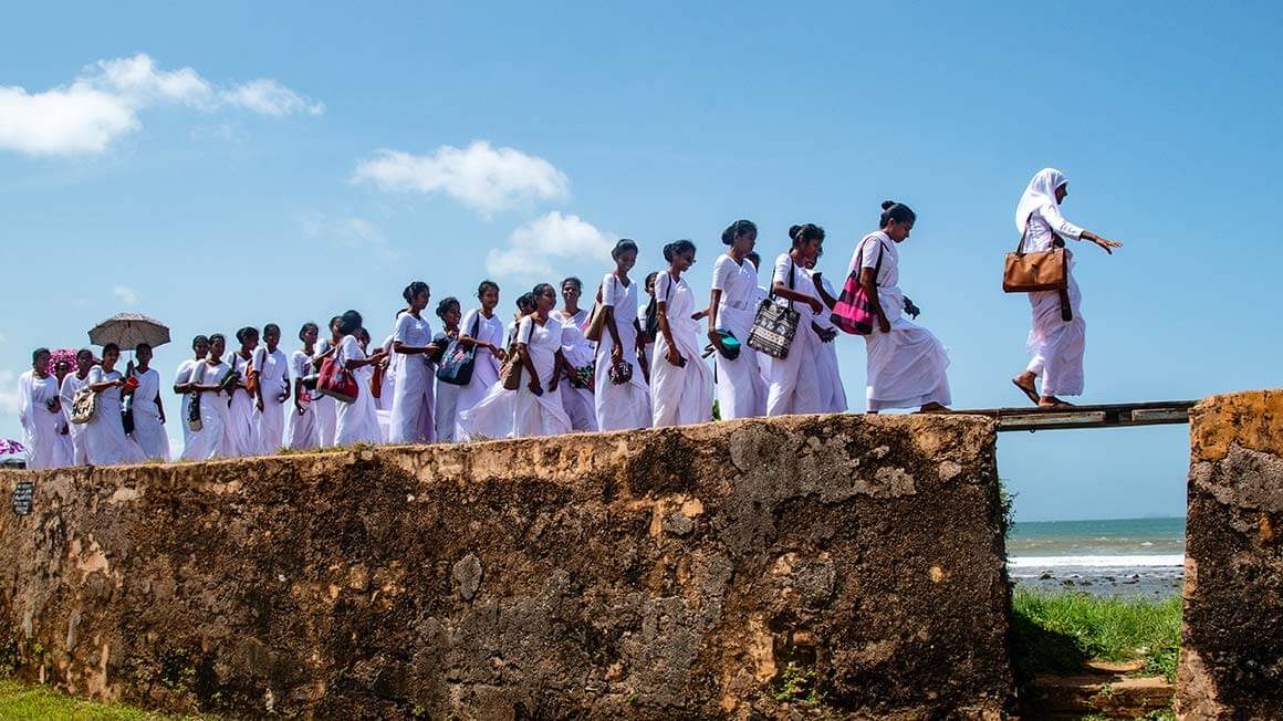 Sri Lankan women dressed in white crossing raised path