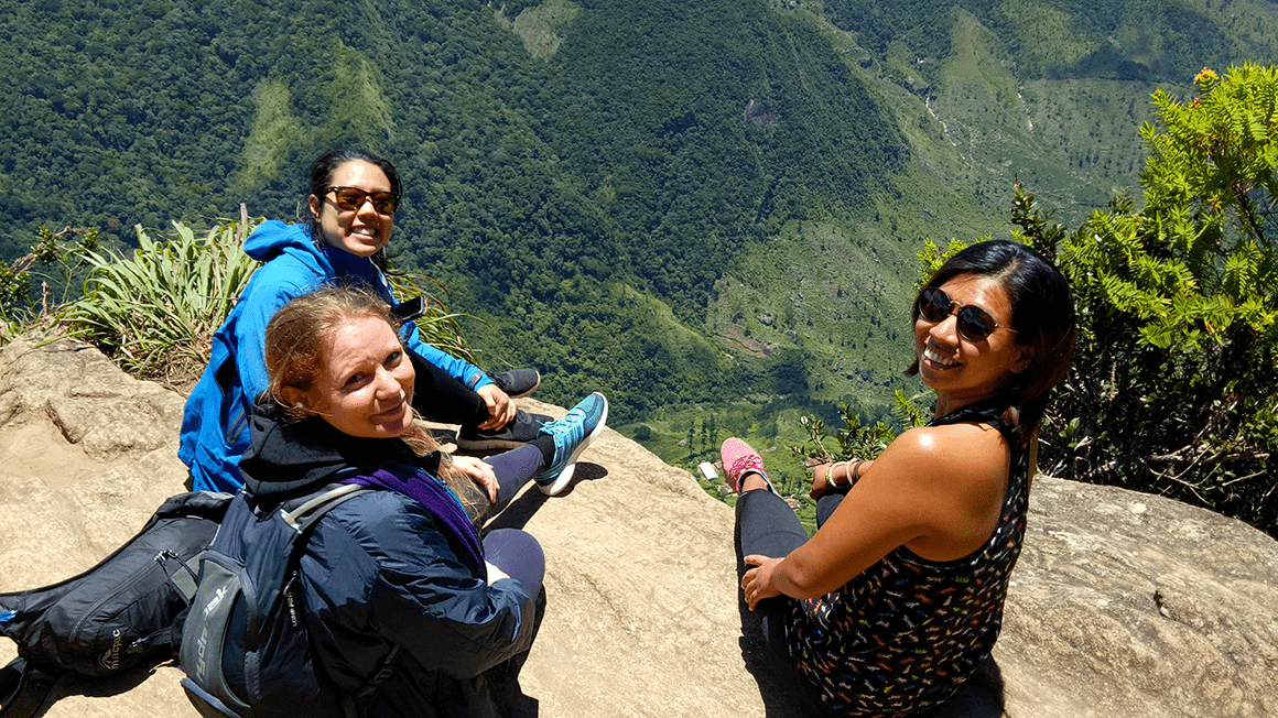 Naome and two women looking back on rock overlooking hill