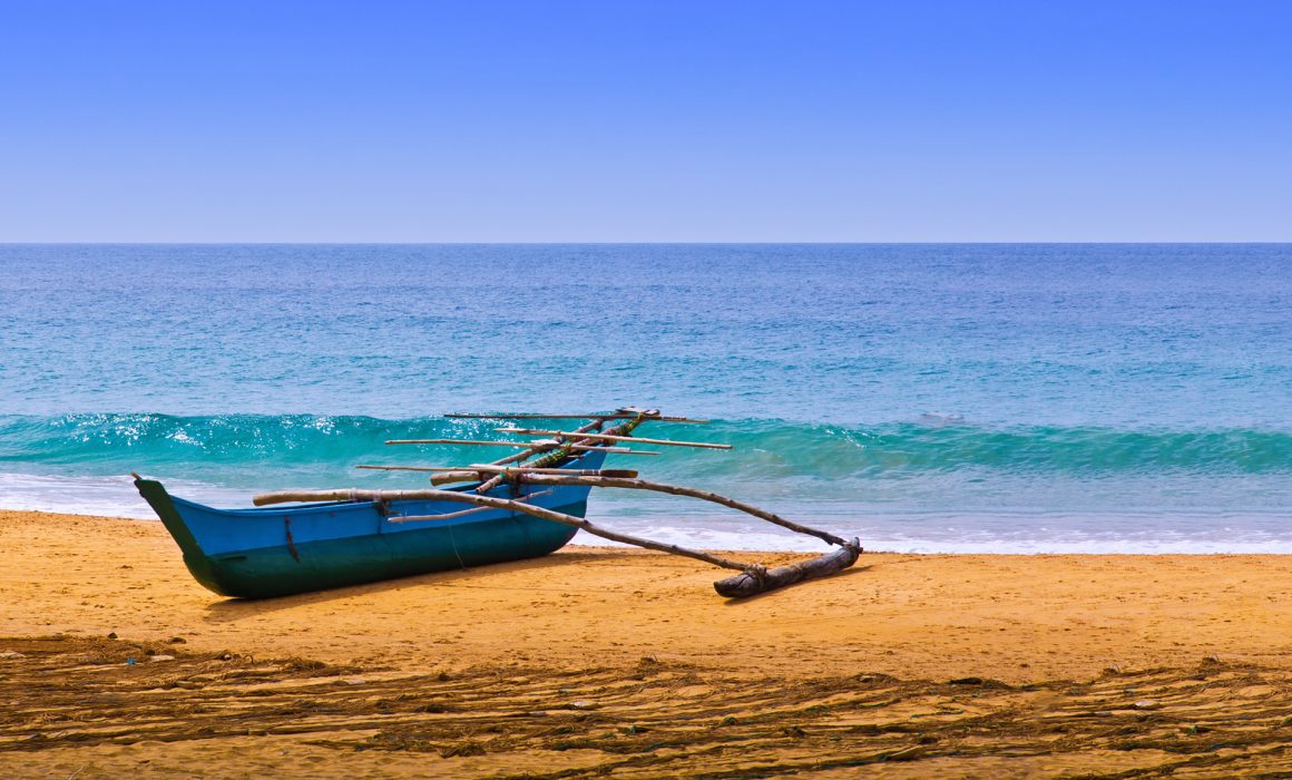 Fisherman's blue boat on sandy beach with wave coming in