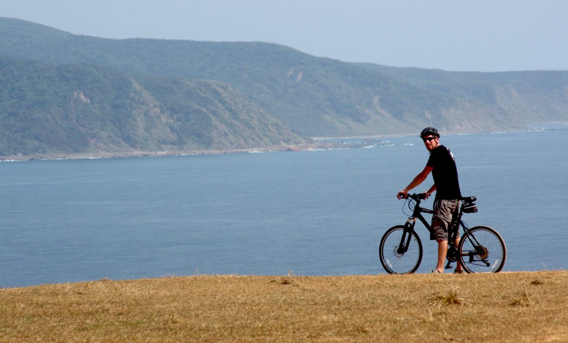 Cyclist parked with bike in front of water and mountains