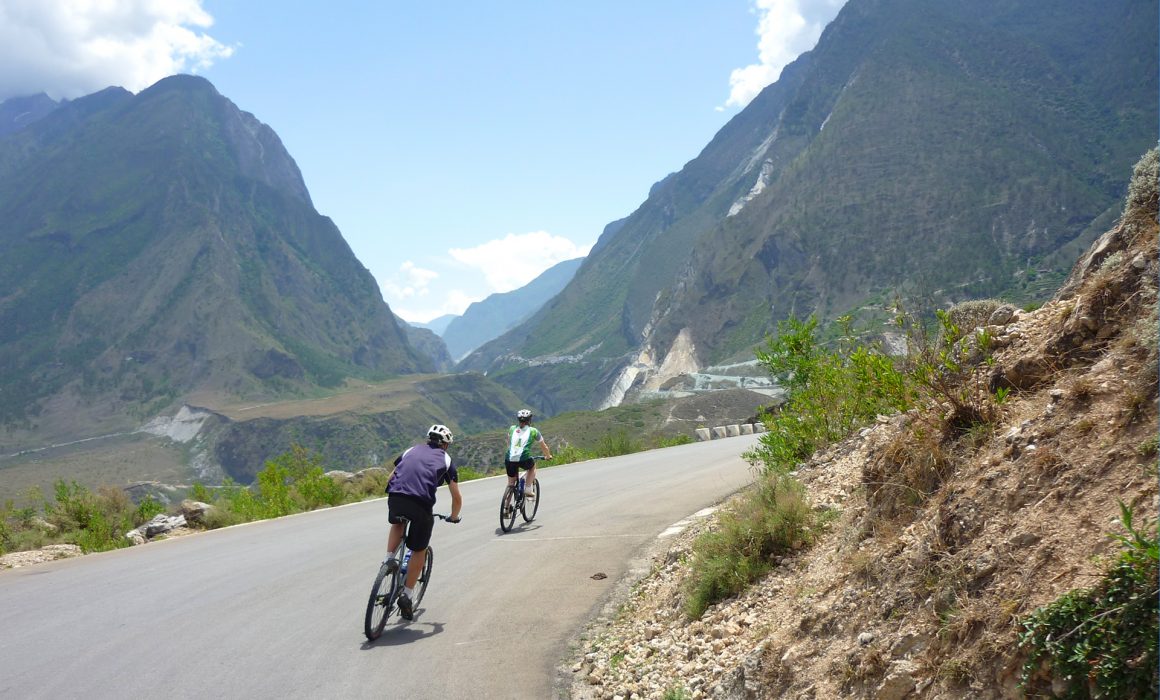 Two cyclists riding around curve near Tiger Leaping Gorge