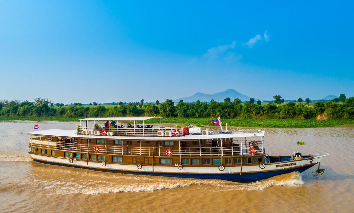 Riverboat on Mekong River with mountains and trees in background