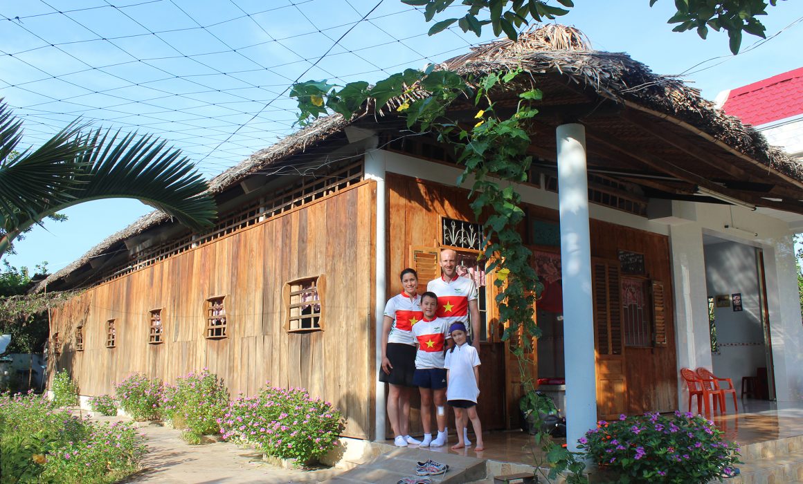 Family with two children in front of local house wearing Vietnam cycling jerseys