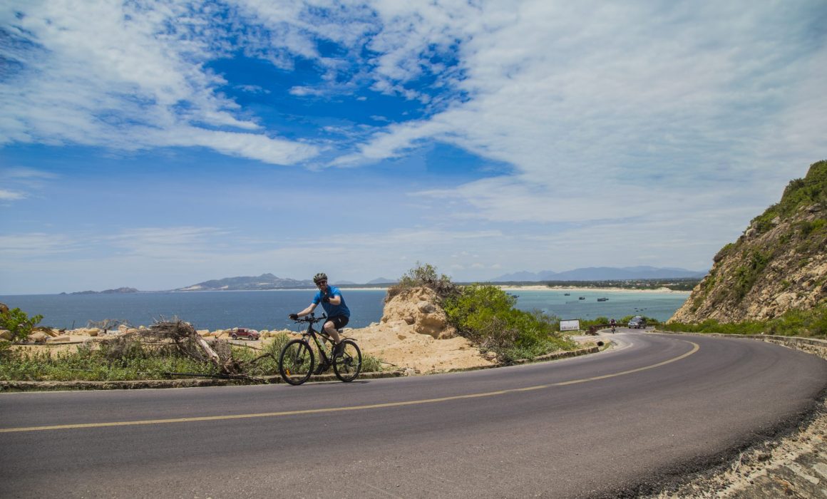 Cyclist rounding corner of Vietnam Ocean Road with water in the background