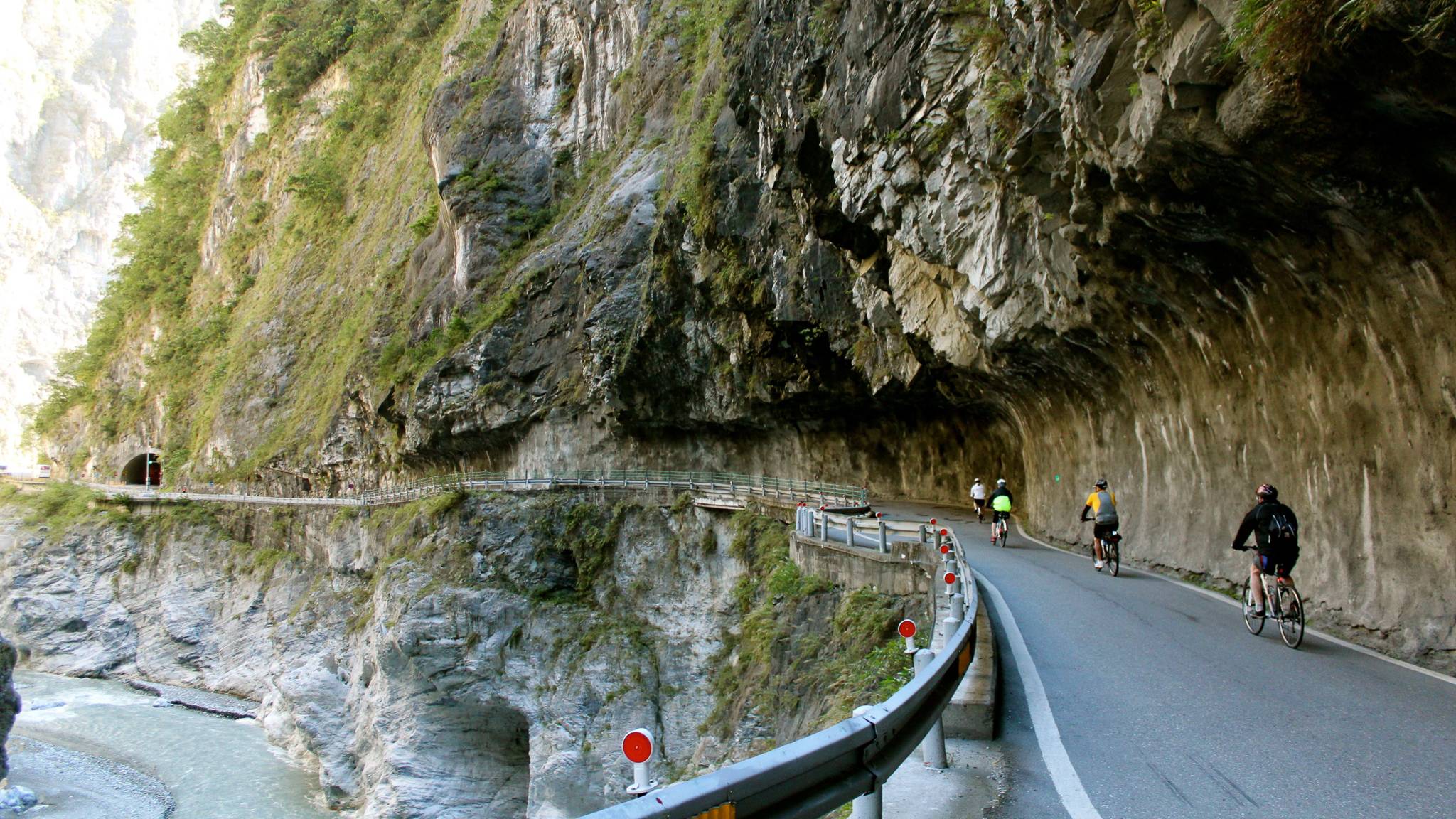 Four cyclists riding on road through Taroko Gorge in Taiwan